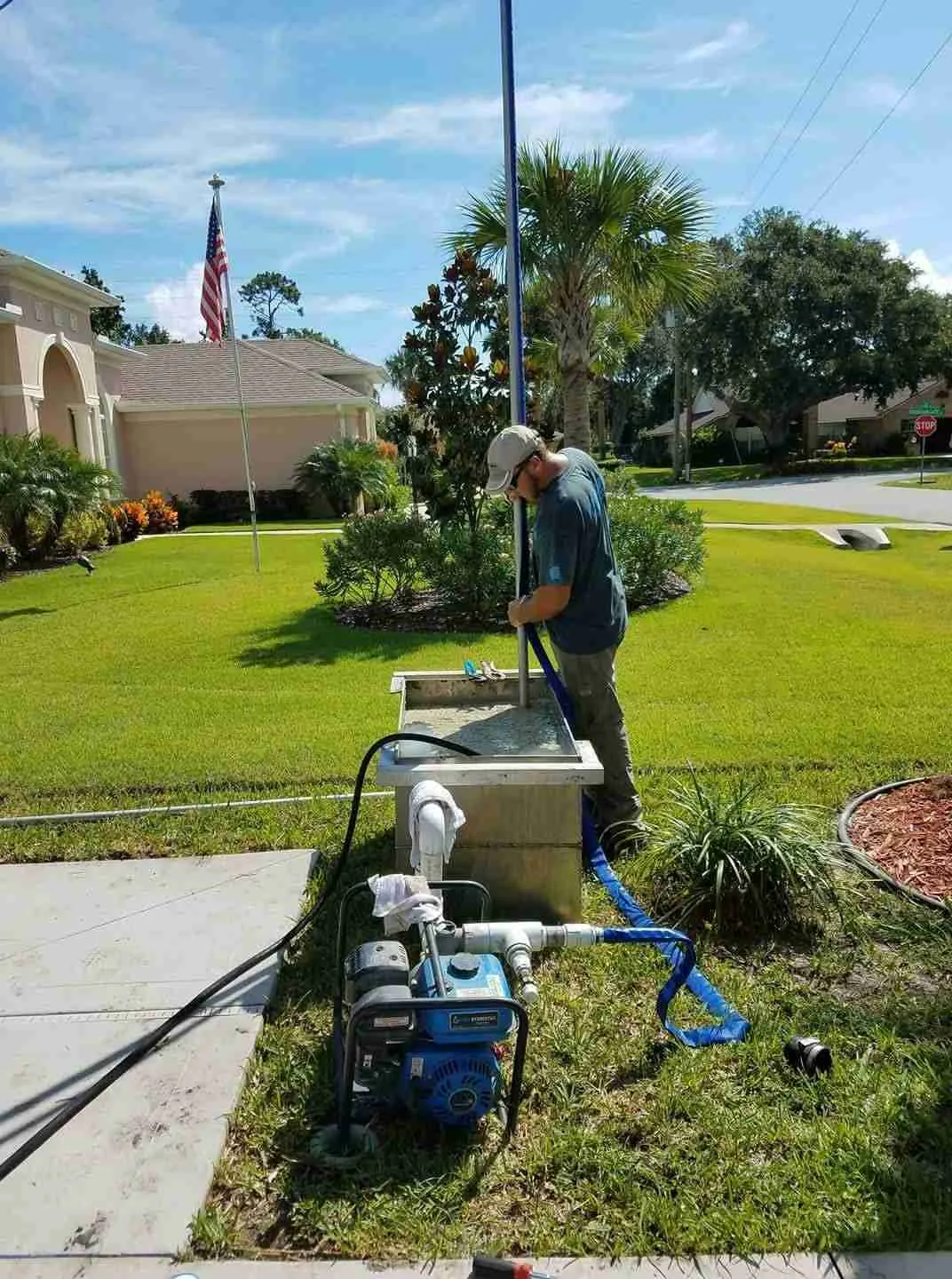 WaterCare technician guides well pipe into a mud tank during residential well drilling
